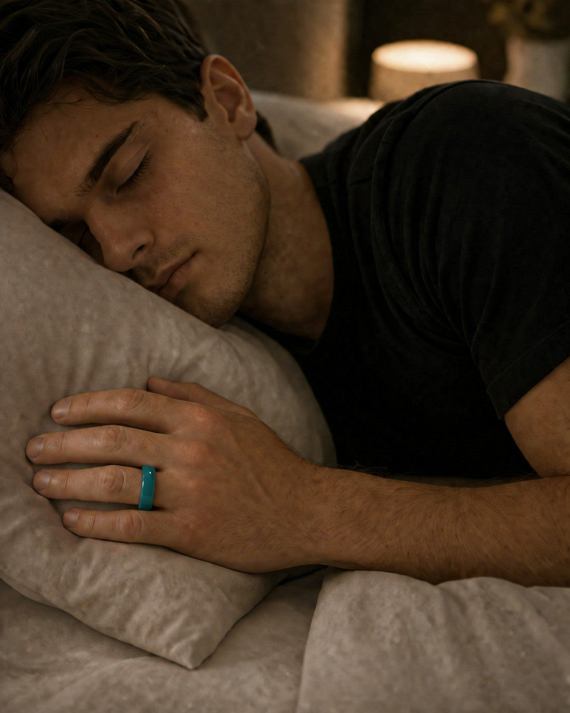 Man asleep wearing the Kayza PRO teal smart ring for overnight sleep tracking